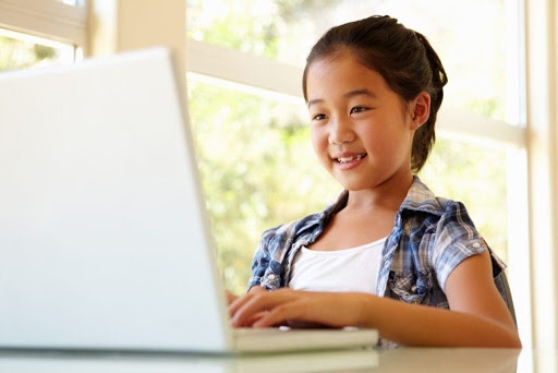 Young child sitting in front of a laptop computer
