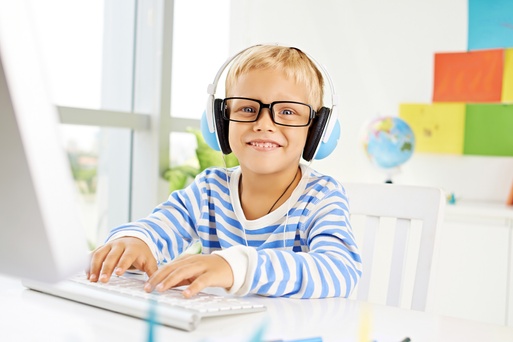 Young child with headphones on sitting in front of a laptop